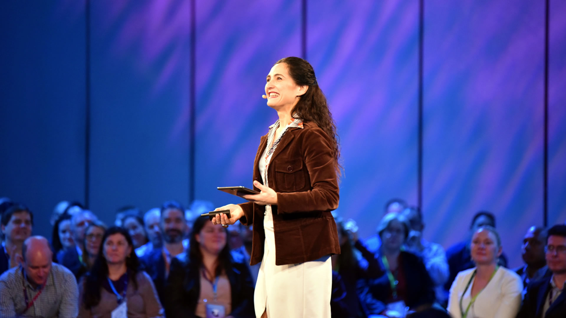 Photo of Josephine Palermo speaking on stage in front of hundreds of people.