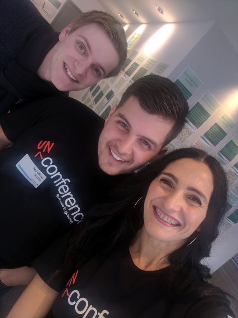 Photo of a group of three people smiling wearing unconference t-shirts.