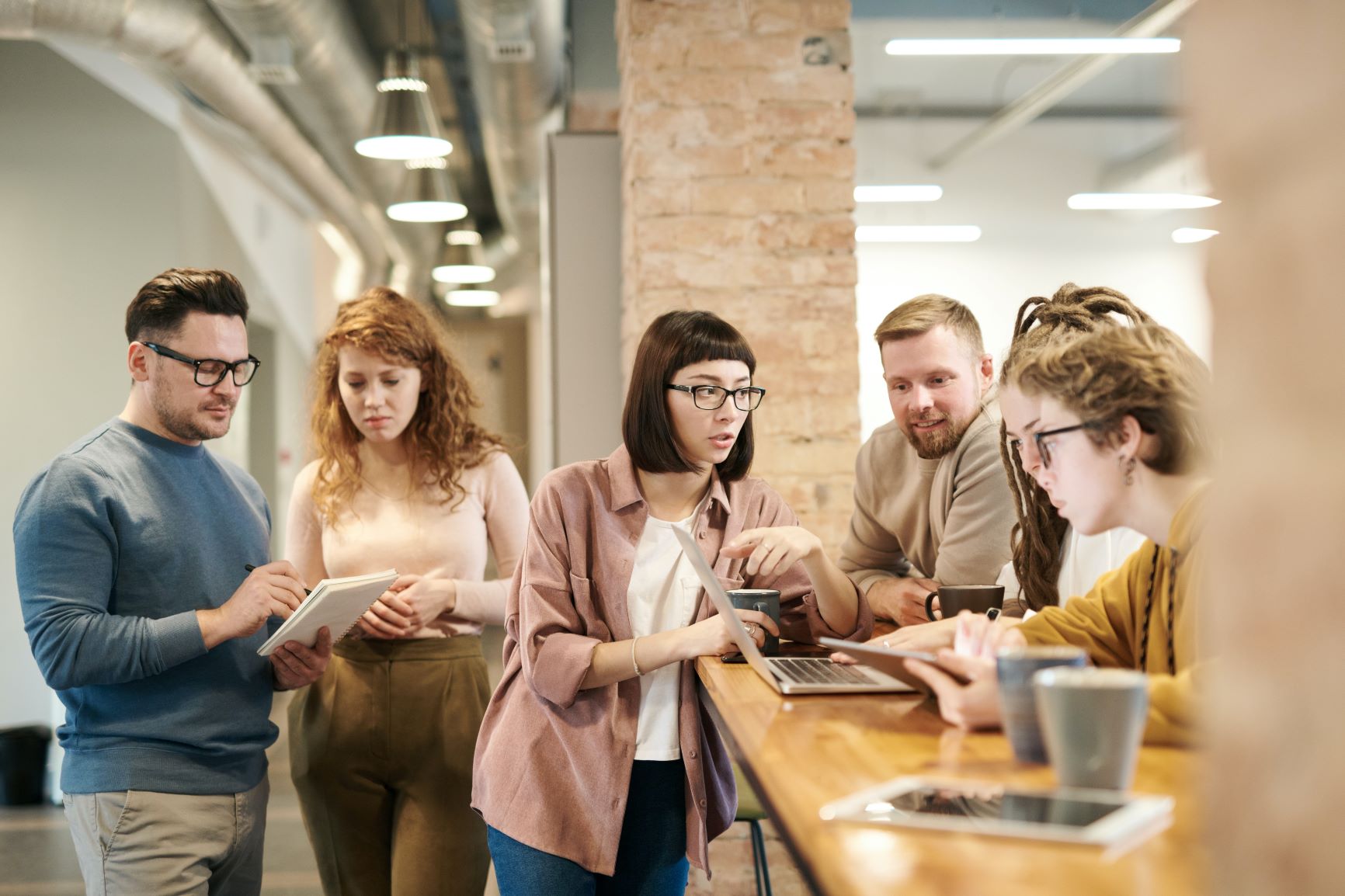 people around tables with laptop