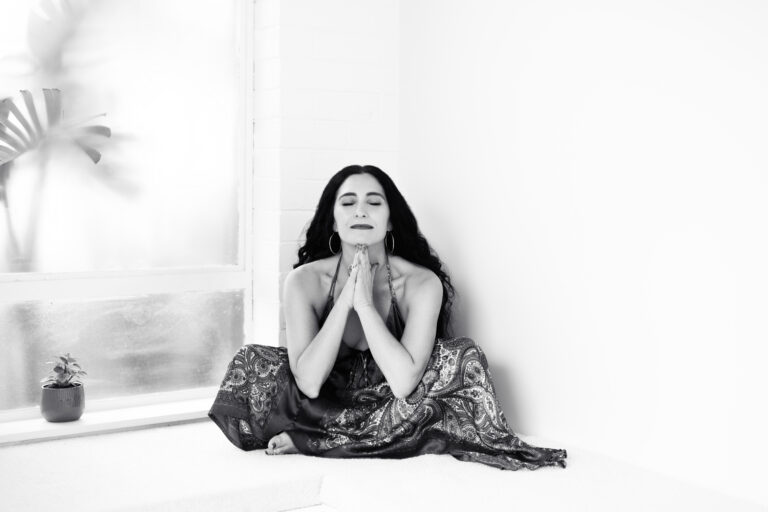woman sitting cross legged hands in prayer position