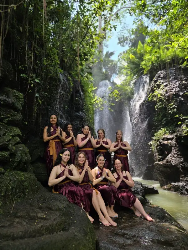 women under a waterfall at a Bali water temple